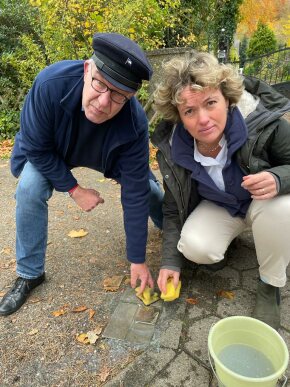 Astrid Hennies und Diakon Franz P. Sauerteig putzen den Stolperstein